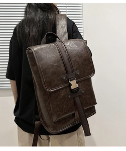 Rear view of a model wearing a dark brown vintage PU leather backpack with buckle straps