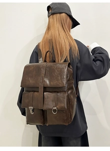 Dettaglio dello zaino vintage in pelle marrone scuro con fibbie metalliche e doppie tasche