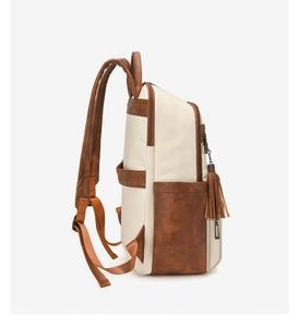 Detail view of cream and brown backpack with side zipper pocket and tassel charm