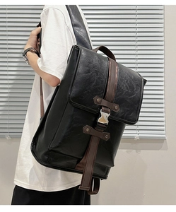 Side view of a black vintage leather backpack with brown straps worn by a male model
