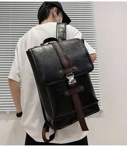 Man wearing a large black urban backpack with brown straps and silver metal buckle