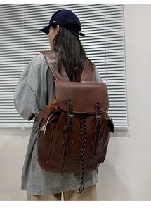 Detail view of large vintage dark brown leather backpack with drawstring and plush bear charm