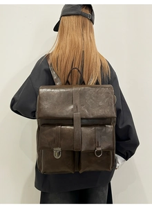 Dettaglio dello zaino vintage in pelle marrone con tasche multiple indossato da modella