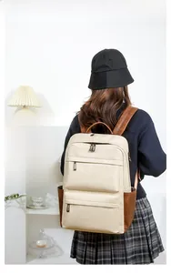 Vue arrière d'un grand sac à dos en similicuir crème et marron porté par un mannequin