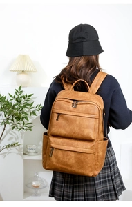 Sac à dos en similicuir marron avec poches zippées vu de dos sur un modèle