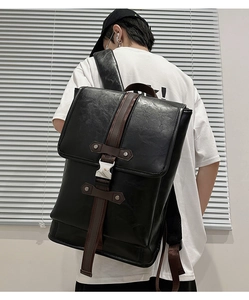 Close-up of the black backpack's vintage metal buckle and contrasting brown straps