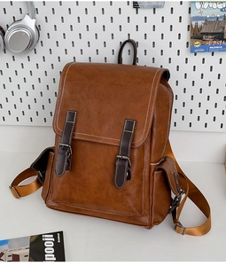 Detail view of vintage brown leather backpack with buckle straps and large front pocket