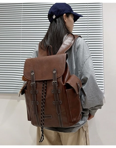 Detail view of vintage brown leather backpack with contrast stitching and drawstring closure