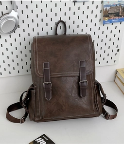 Close-up of vintage brown leather backpack with contrast stitching on white pegboard