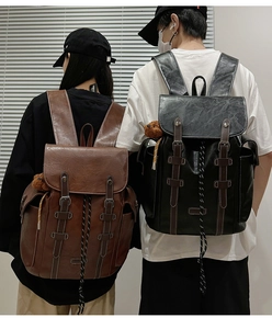 Detail of vintage backpacks with leather texture, decorative straps and plush bear pendant