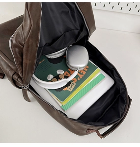 Top view of brown retro leather backpack showing spacious interior with books and headphones