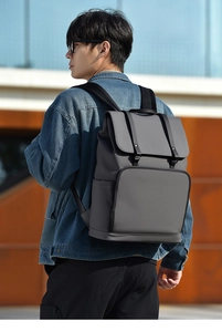 Minimalist grey commute backpack shown in use on a city street background