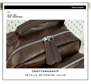 Detail of dark brown leather backpack showing double silver zippers and reinforced handle