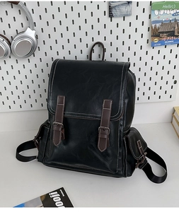 Detail of vintage black leather backpack with brown buckle straps and white stitching