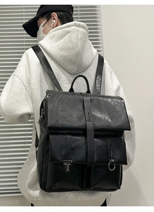 Vista posteriore della modella con zaino vintage in pelle nera e due tasche frontali con fibbie
