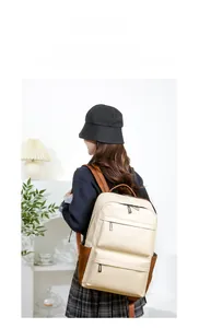 Détail grand sac à dos en cuir crème avec garniture marron sur mannequin dans un intérieur
