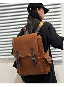 Detail view of vintage brown leather backpack showing flap closure and contrast stitching