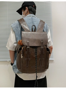 Rear view of vintage dark brown leather backpack with bear charm on a male model