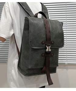 Detail view of dark grey vintage workwear backpack featuring metal buckles and textured leather