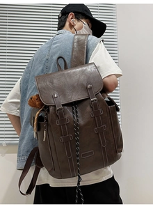 Detail of vintage brown leather backpack with buckle straps and plush bear charm