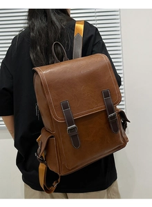 Detail of vintage brown leather backpack showing double straps and metallic buckle hardware