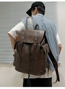 Detail showing vintage brown leather backpack with contrast stitching and metal buckles