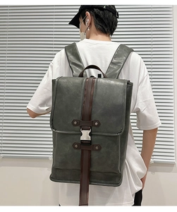 Detail of dark green matte leather backpack with brown straps and silver metal buckles