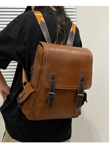 Detail of vintage brown leather backpack with contrast stitching and metal buckle straps