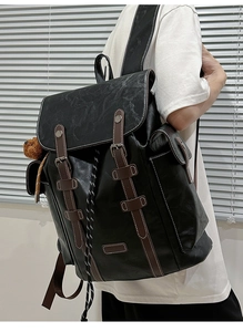 Detail of vintage black leather backpack showing side pocket and bear charm accessory
