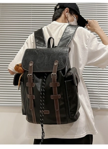 Detail of vintage black leather backpack with brown straps and cute bear pendant charm