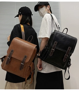 Detailed view of two vintage PU leather backpacks in brown and black with buckle straps