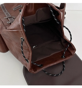 Detail of dark brown leather backpack with drawstring closure and white contrast stitching