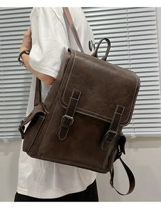 Detail of dark brown leather backpack featuring vintage buckle straps and side pocket