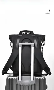 Detail of black business backpack with a luggage strap fixed on a silver suitcase handle