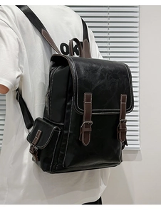 Close-up of retro black PU leather backpack with brown buckle straps and white stitching
