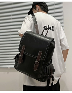 Close-up of retro black PU leather backpack with brown buckle straps and white stitching