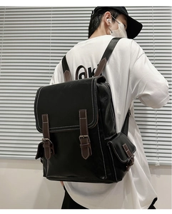 Black vintage leather backpack with brown buckle detail and contrast white stitching on model
