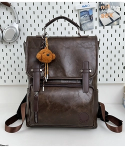 Detail view of vintage brown PU leather backpack with teddy bear charm and front pocket