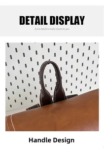 Detail view of the brown leather backpack carry handle with contrast stitching