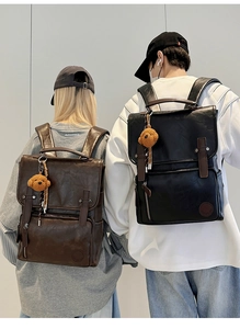 Close-up of retro PU leather backpacks in black and brown with cute plush bear charms