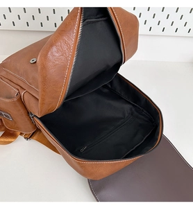 Detail view of the brown leather backpack interior showing black lining and zip pocket