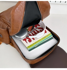 Top view of brown PU leather backpack interior showing laptop and books storage