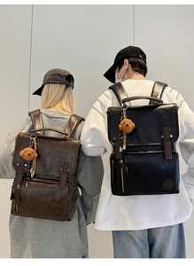 Detail of vintage PU leather backpacks in black and brown with cute bear charms
