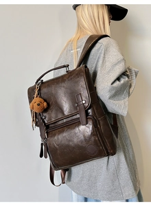 Detail of dark brown vintage PU leather backpack with teddy bear pendant on model