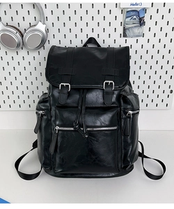 Detail view of black faux leather backpack with drawstring closure and silver buckles