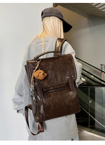 Detail of vintage brown PU leather backpack featuring flap closure and plush bear charm