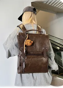 Detail view of vintage dark brown PU leather backpack with plush bear charm and buckle