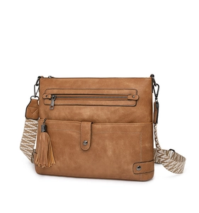Macro shot of brown retro crossbody bag featuring ethnic woven strap and tassel details