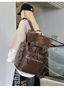 Detail of dark brown vintage faux leather backpack with flap closure and multiple pockets