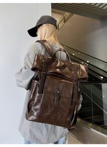 Side view of large vintage dark brown PU leather backpack with buckle straps and pockets